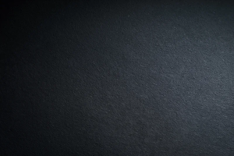 Dark charcoal matte surface filling the frame with subtle texture and even lighting