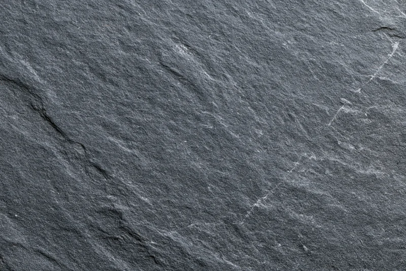 Dark grey slate stone surface filling the frame with natural texture and cracks