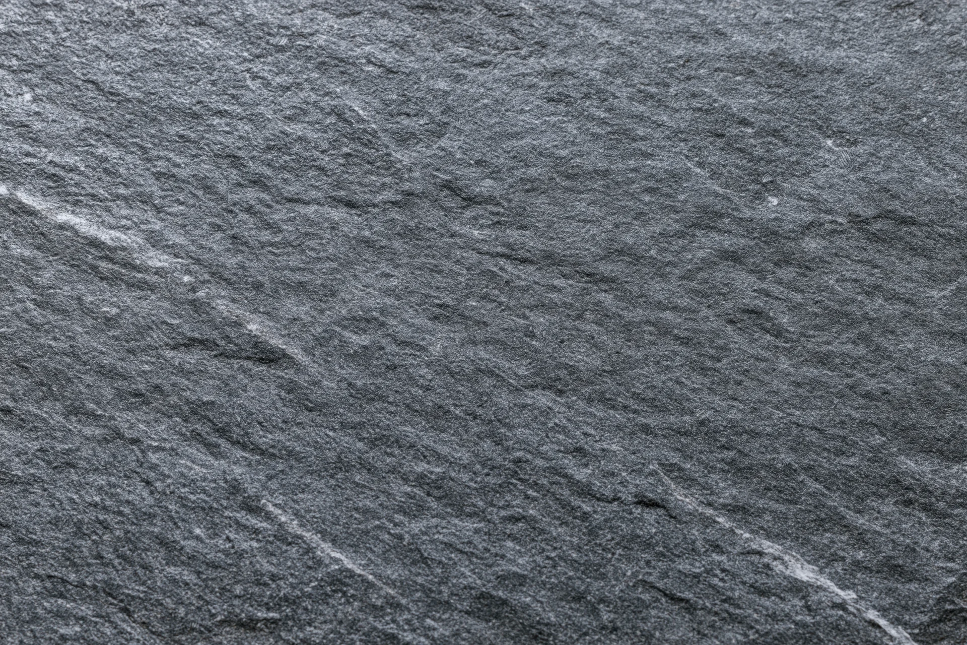 Dark grey slate stone surface with natural texture and veins filling the frame