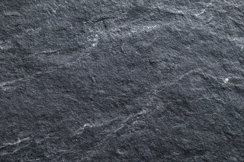 Dark grey slate stone surface filling the frame with natural texture and veining