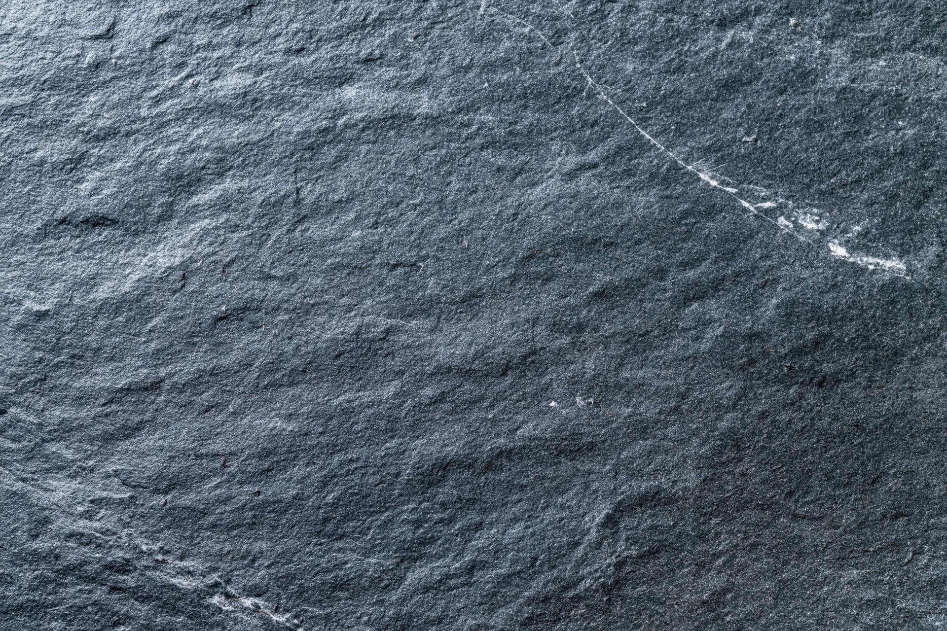 Dark grey slate stone surface filling the frame with natural texture and veins