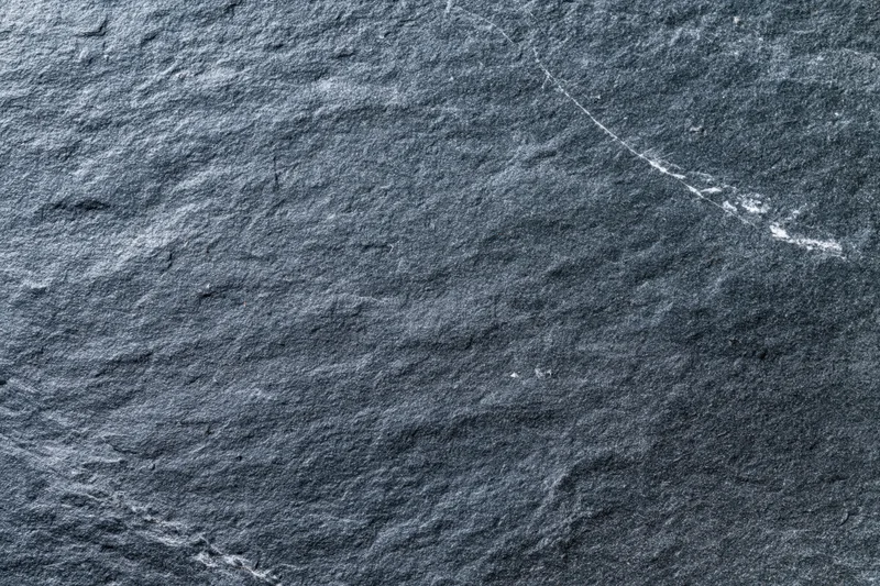 Dark grey slate stone surface filling the frame with natural texture and veins