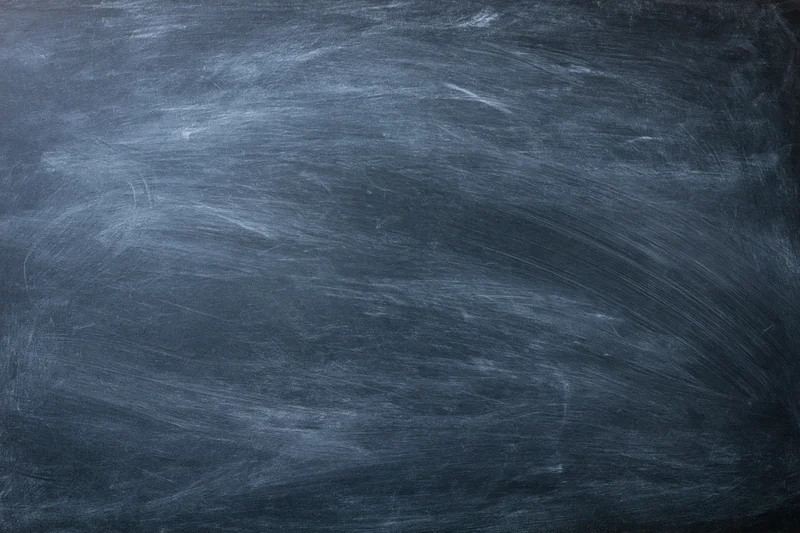 Dark slate chalkboard surface with faint erased chalk marks and smudges, showing texture and residue from use