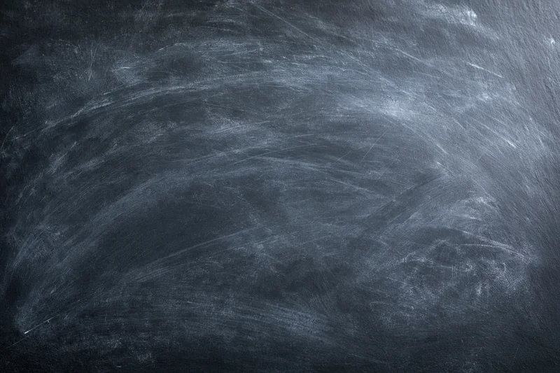 Dark slate chalkboard surface with faint erased chalk marks and smudges