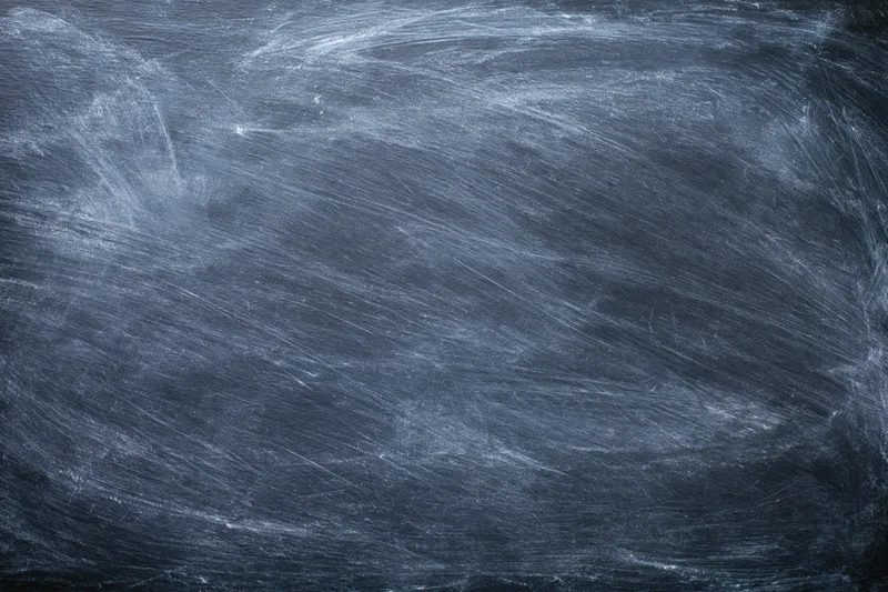 Dark slate chalkboard surface with faint erased chalk marks and smudges