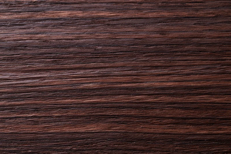 Dark walnut wood surface with visible grain pattern filling the frame