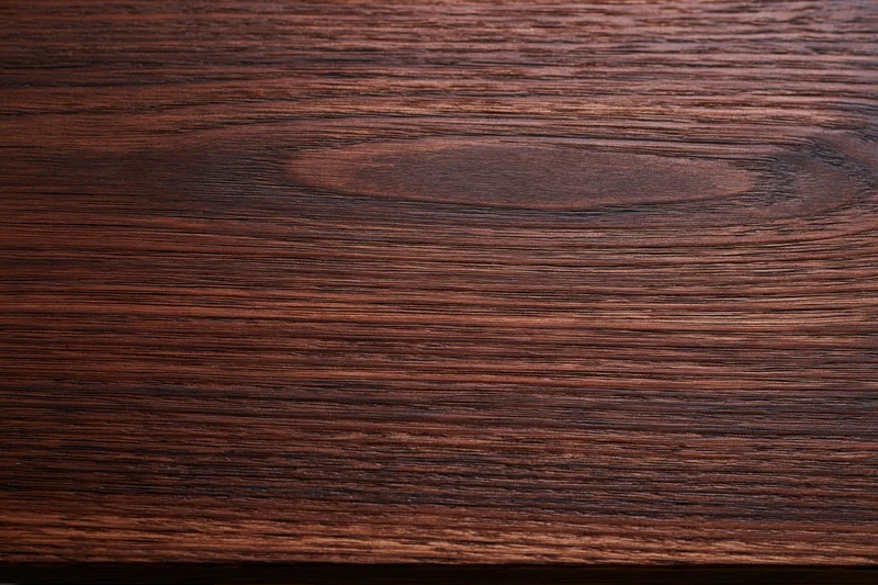 Dark walnut wood surface with visible grain pattern filling the frame