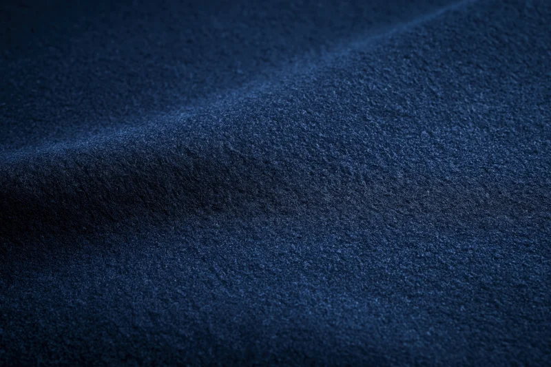 Closeup of deep navy blue textured fabric surface with folds and waves