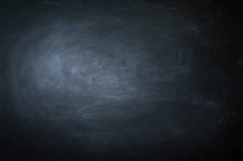 Close-up of an empty blackboard surface with smudged chalk residue and dark gray texture filling the frame