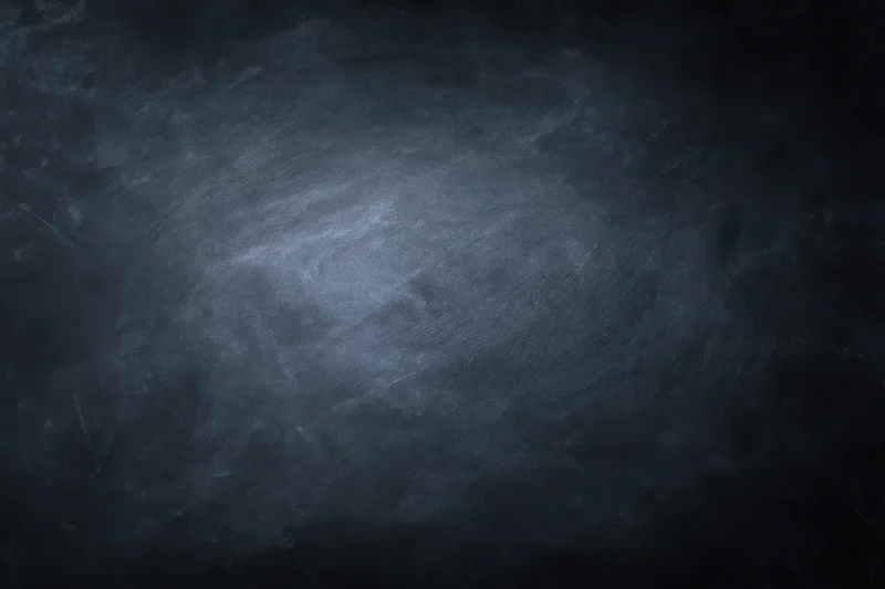 Close-up of an empty blackboard surface with smudged chalk marks and dark gray texture filling the frame