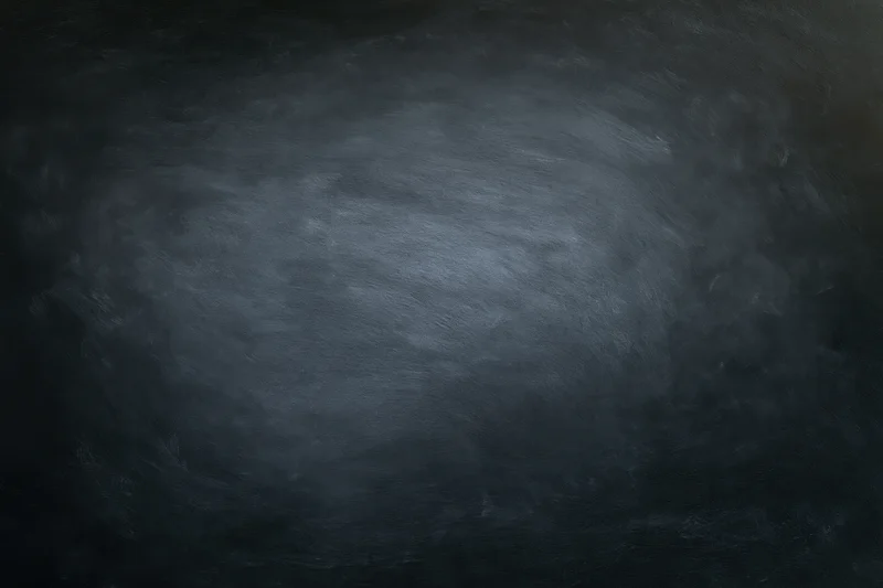 Close-up of an empty blackboard surface with smudged chalk marks and dark gray texture filling the frame