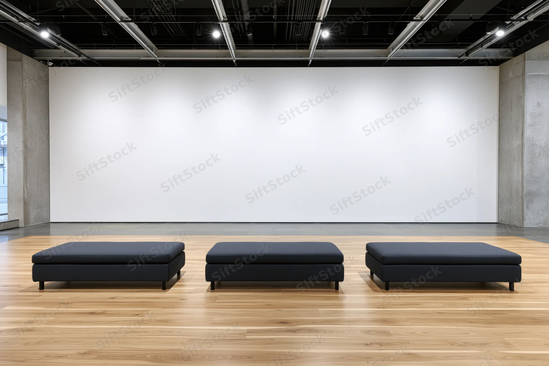 Three black benches arranged in a row in an empty contemporary art gallery with white walls and wooden floor