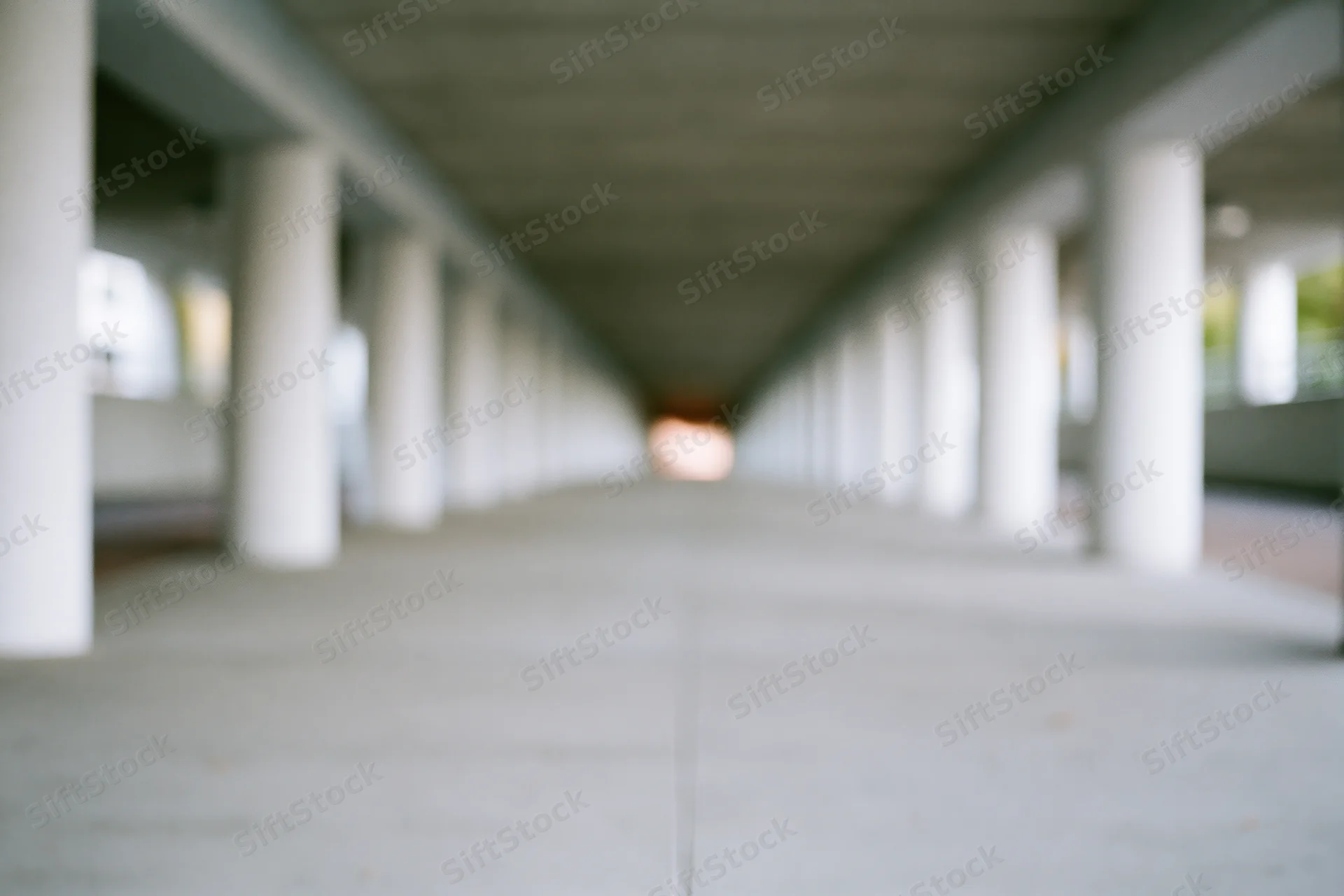 Empty concrete underpass corridor with repeating pillars receding into distance
