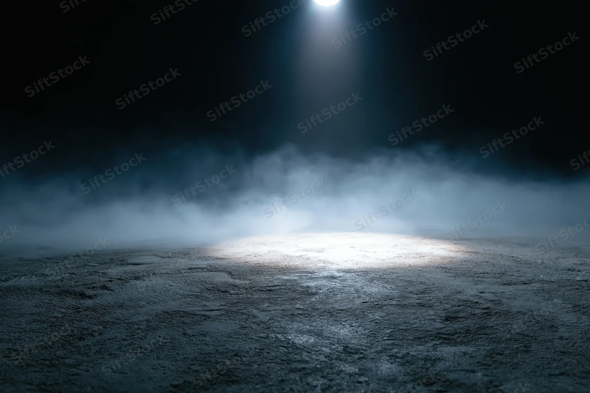 Spotlight illuminating a dark concrete floor with smoke in a stage setting
