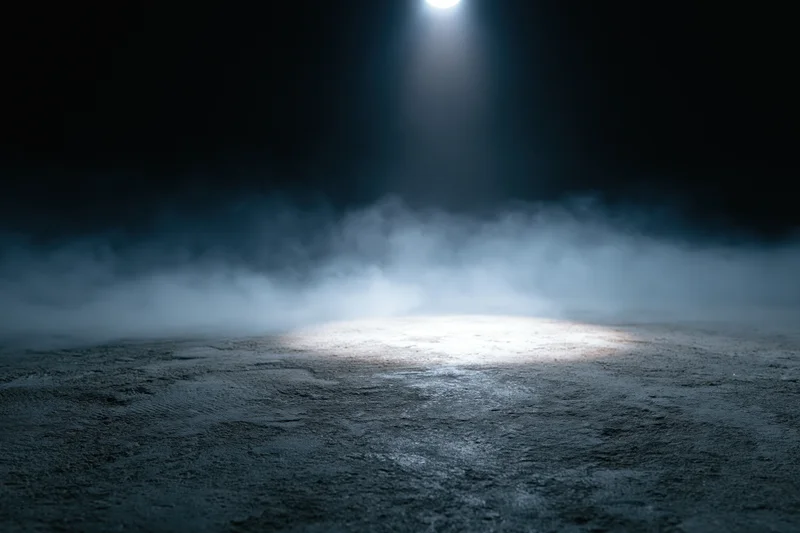 Spotlight illuminating a dark concrete floor with smoke in a stage setting