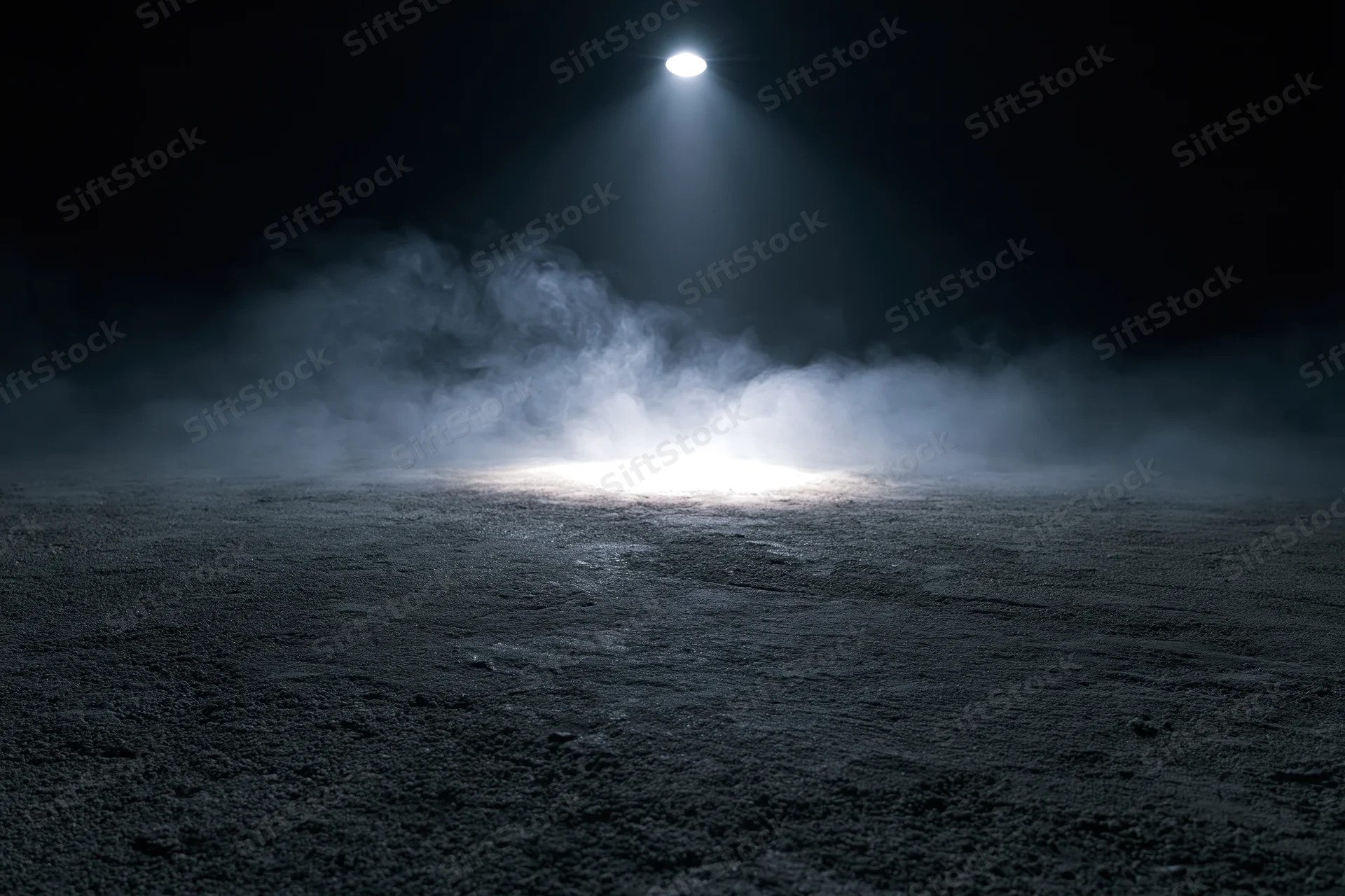Spotlight beam illuminating fog over dark concrete floor in empty space
