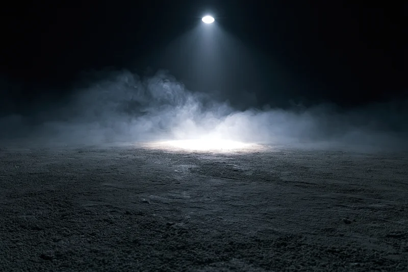 Spotlight beam illuminating fog over dark concrete floor in empty space