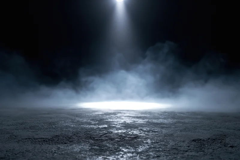 Spotlight beam on dark concrete floor with fog, creating dramatic stage ambiance