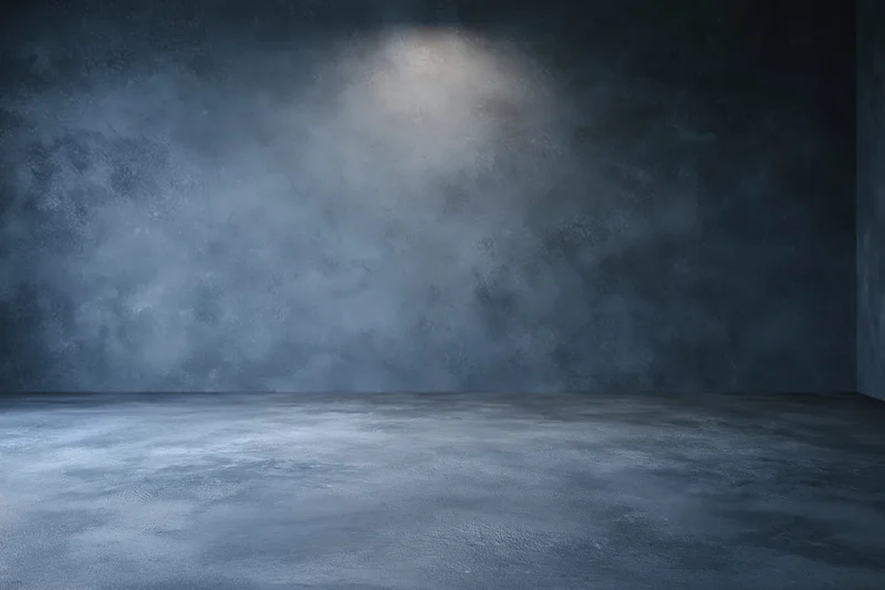 Empty dark grey concrete studio with smooth floor and spotlighted wall
