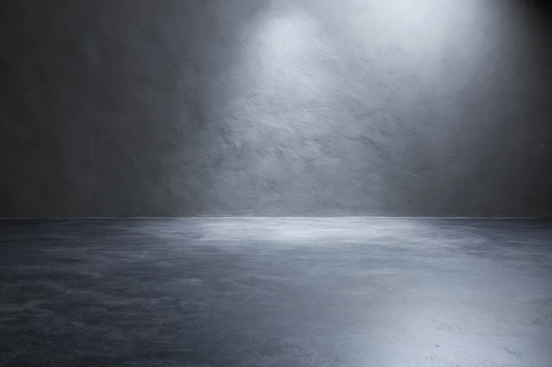 Empty dark grey concrete studio with smooth floor and spotlighted wall