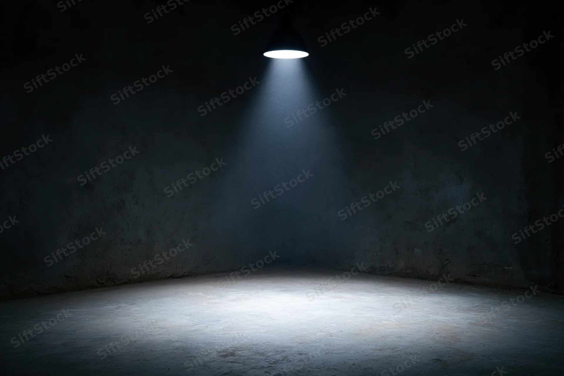 Single spotlight illuminating a corner of an empty dark room with concrete walls and floor