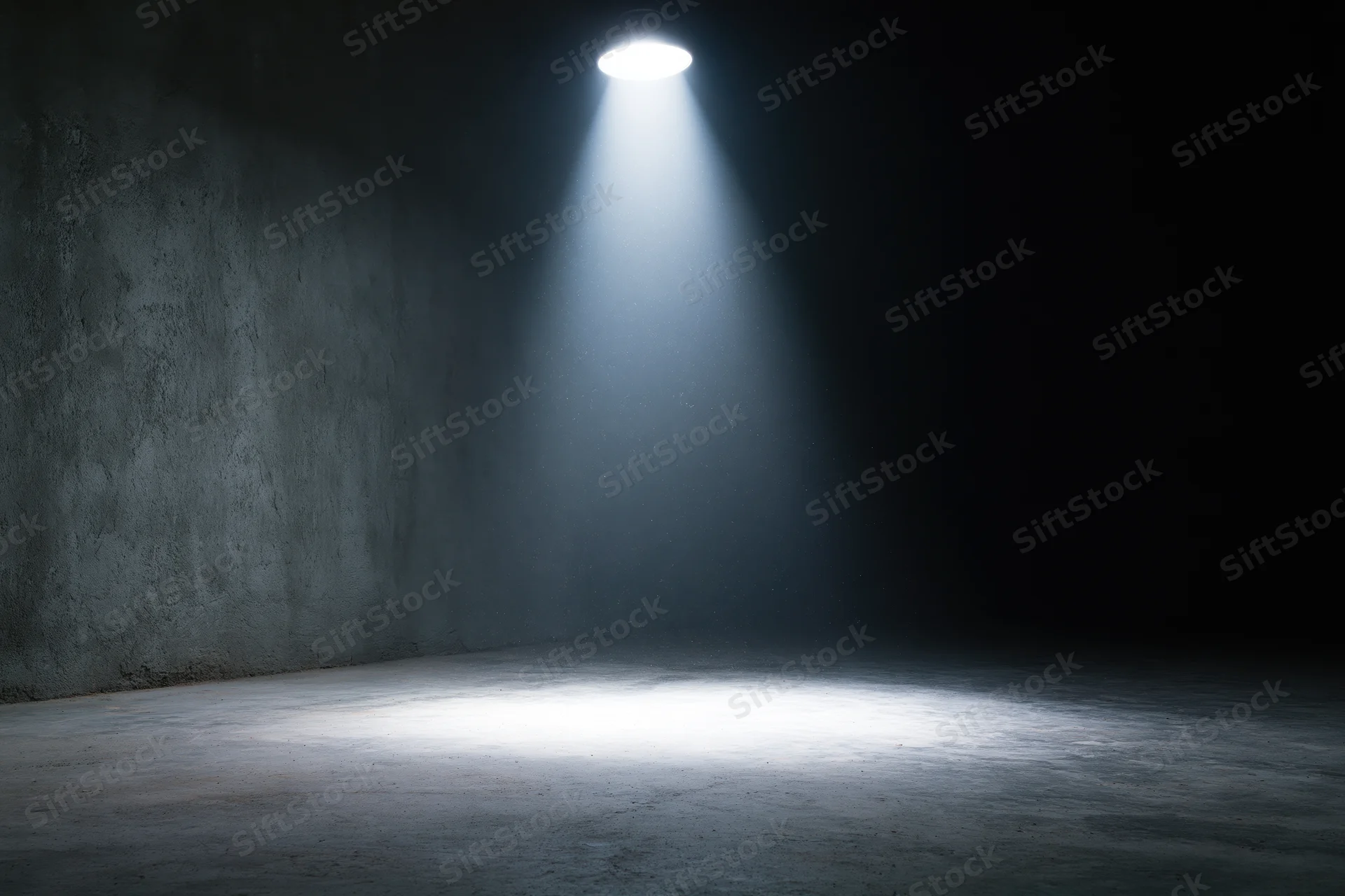 Single spotlight illuminating a dark concrete room interior