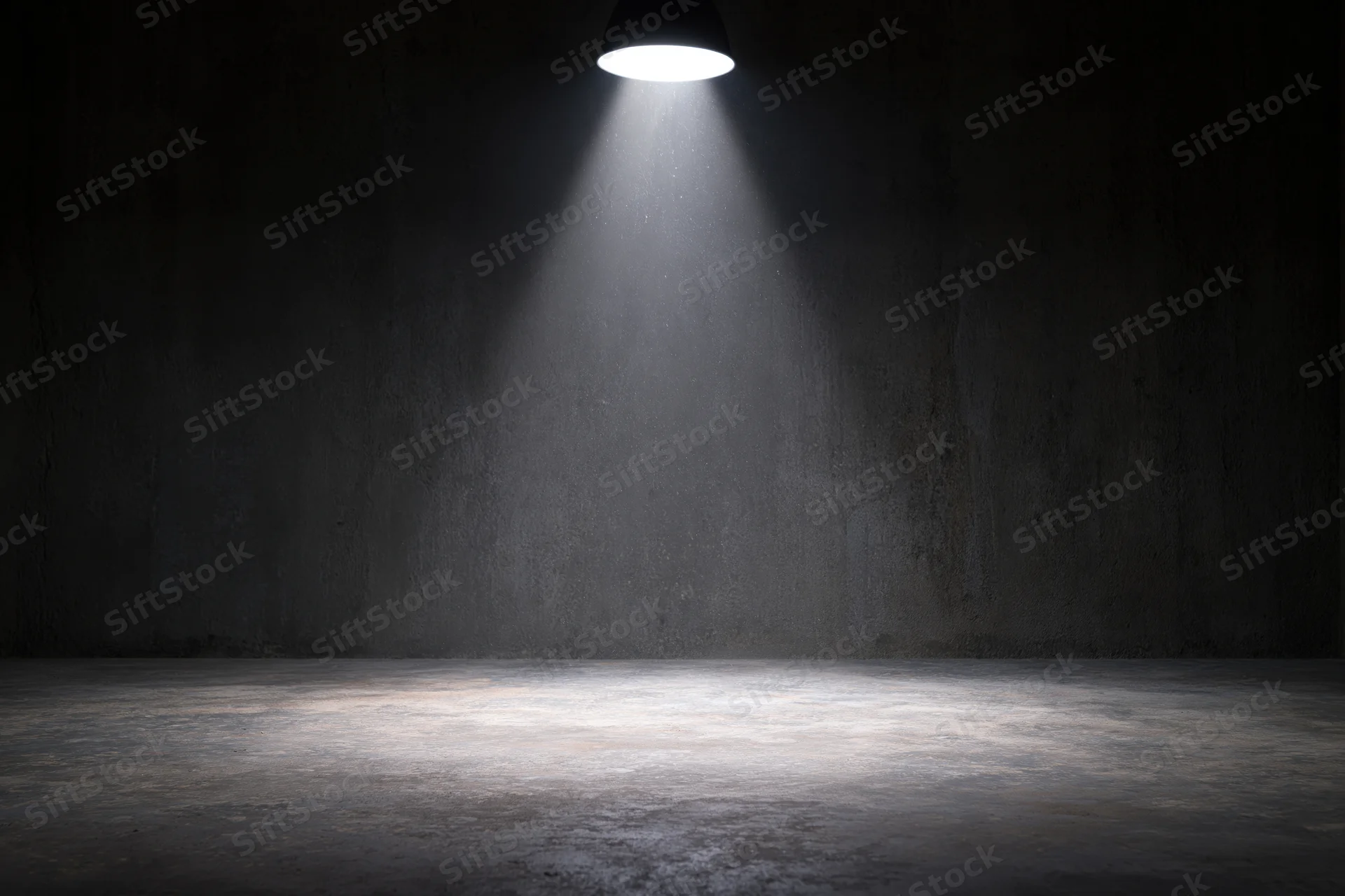 Single spotlight illuminating a dark concrete room interior