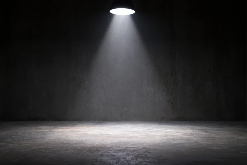 Single spotlight illuminating a dark concrete room interior