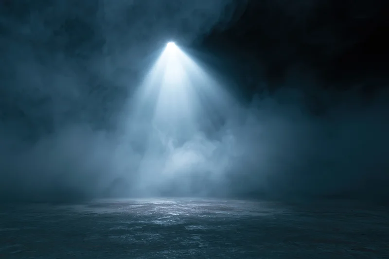 Single spotlight beam illuminating dark stage floor through smoke