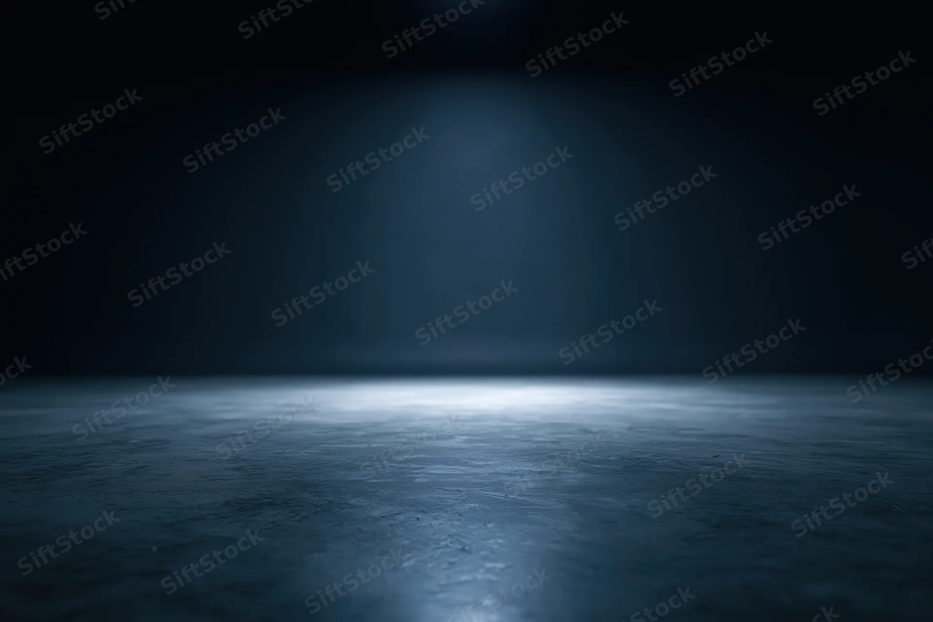 Spotlight on a dark concrete floor in an empty studio space