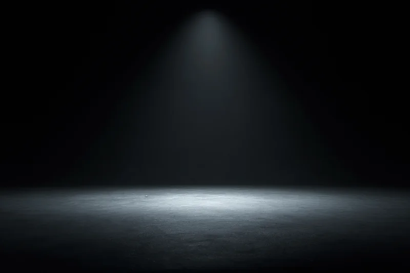 Single spotlight illuminating a dark studio floor, centering on an empty space for display