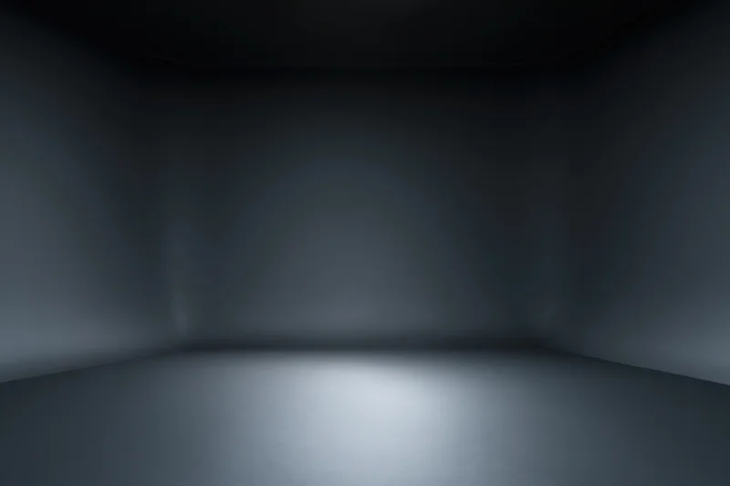 Dark empty studio interior with seamless floor and walls, spotlight on floor creating gradient shadow