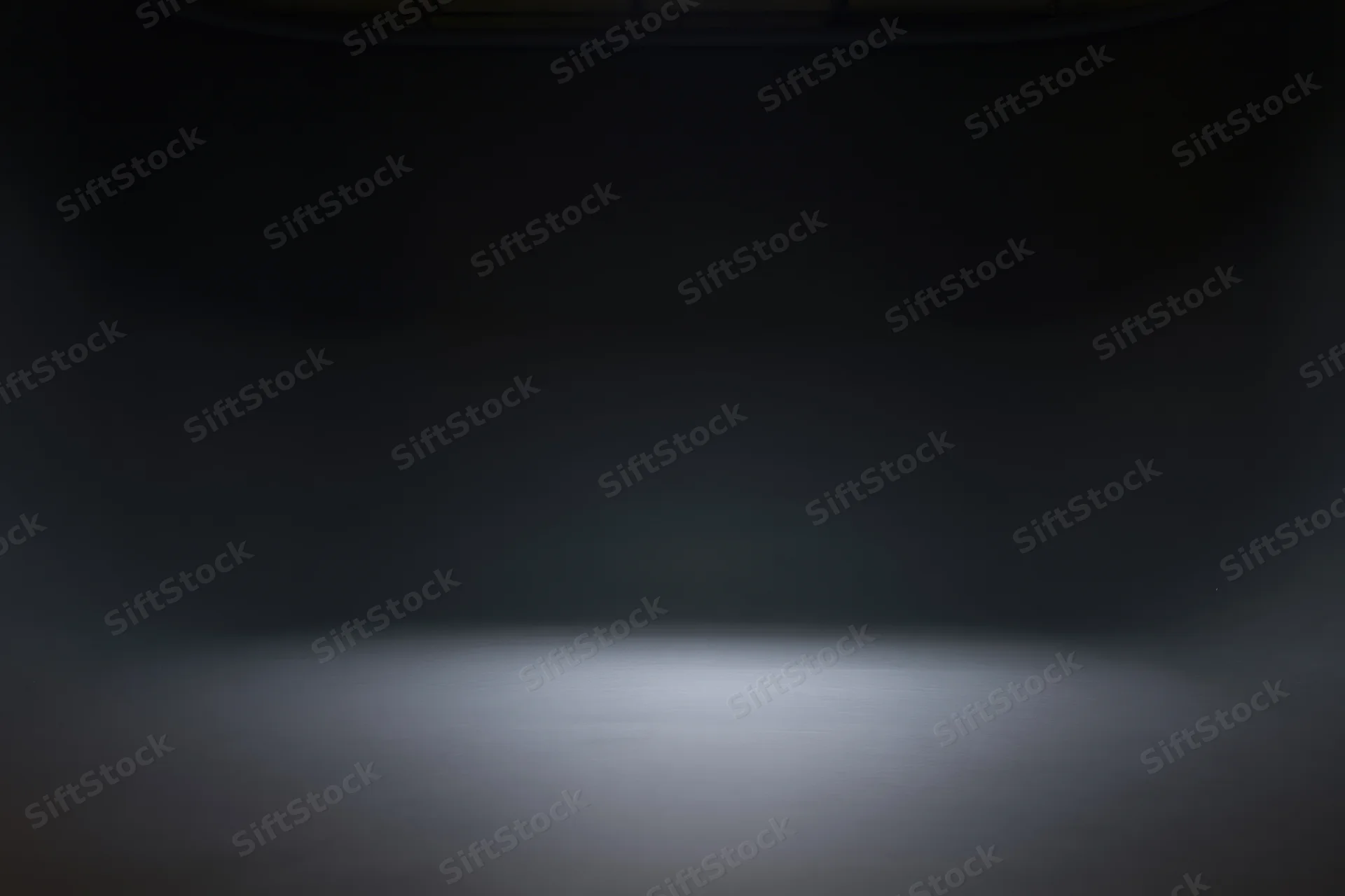 Dark studio space with spotlight on seamless floor, empty interior for product display