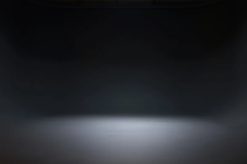 Dark studio space with spotlight on seamless floor, empty interior for product display