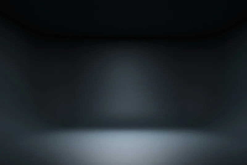 Dark studio interior with seamless curved walls and spotlighted floor, empty space for product display