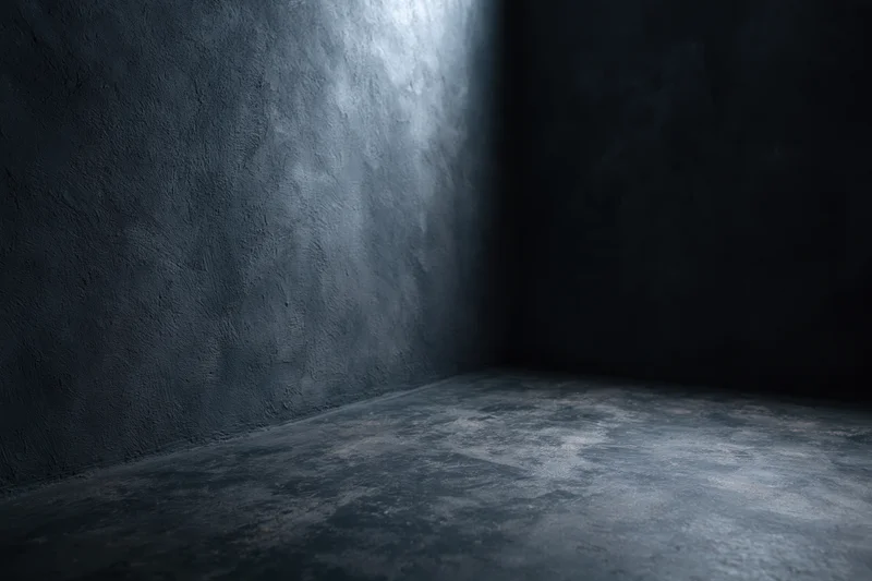 Dark textured concrete corner in empty studio space with dim lighting and shadowed walls
