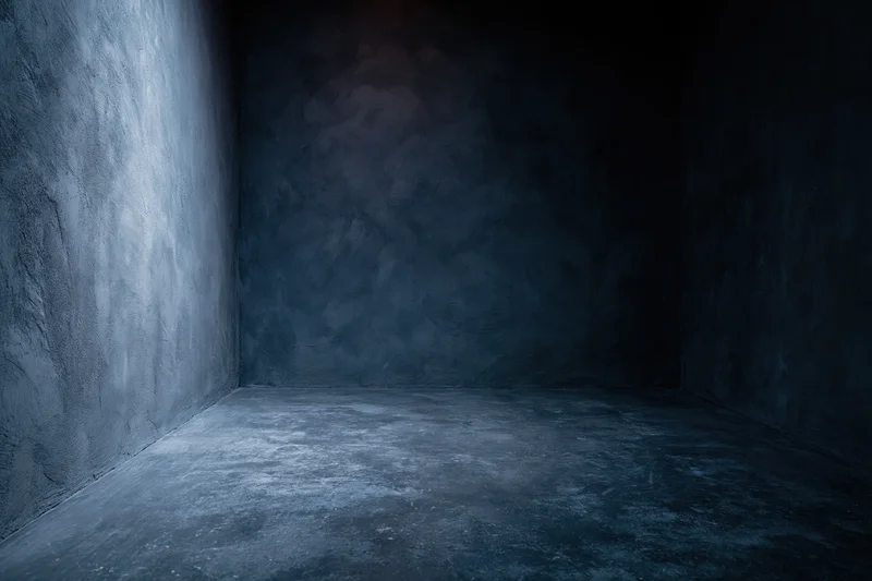 Dark empty studio corner with textured concrete walls and floor