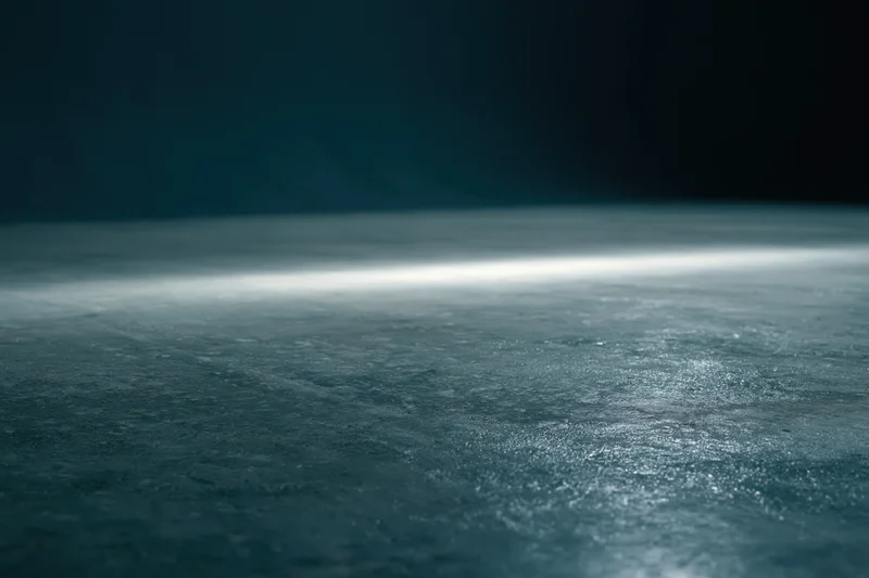 Dark studio floor illuminated by a single low horizontal beam of light