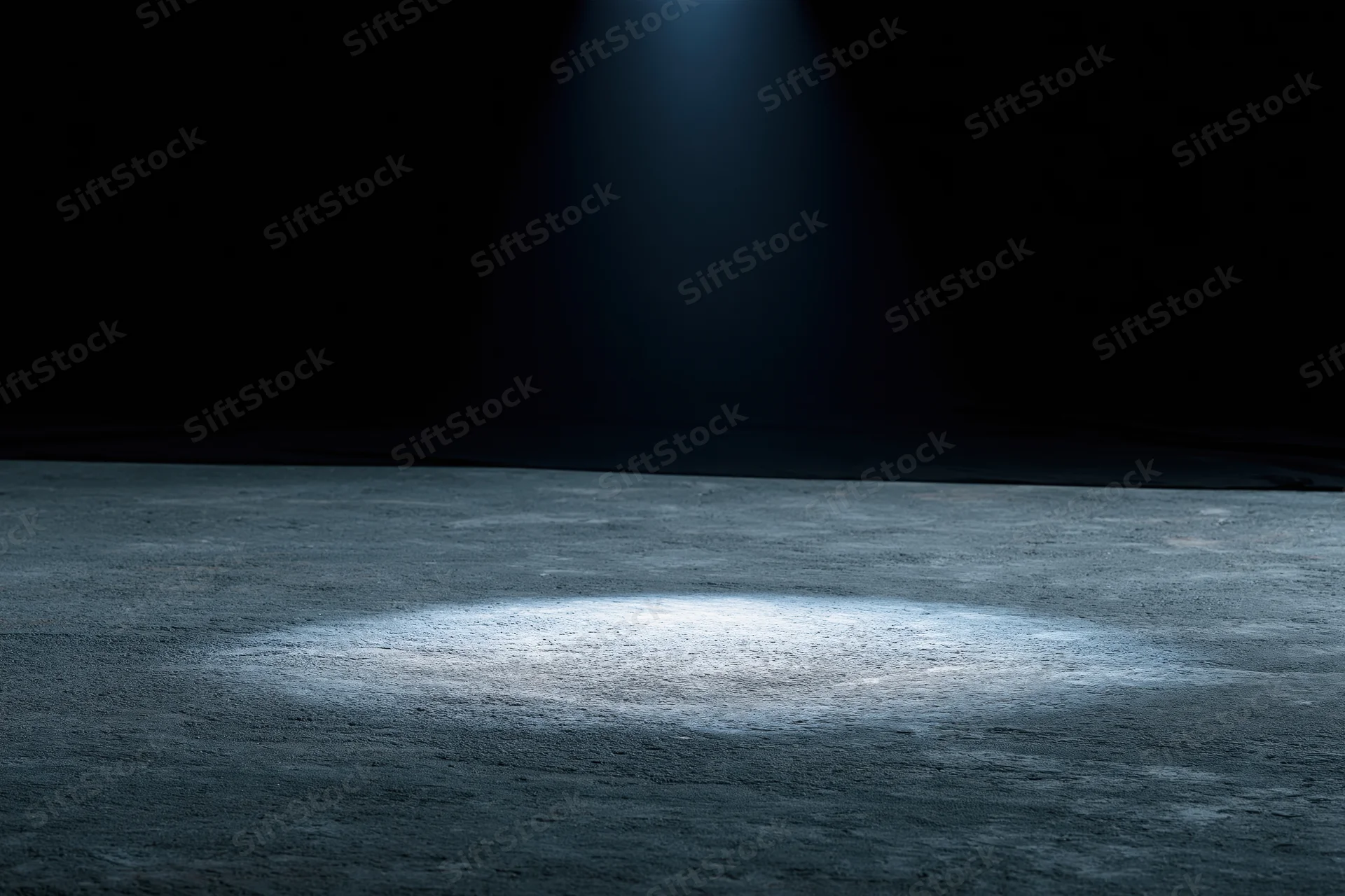 Spotlight on concrete floor in dark studio space