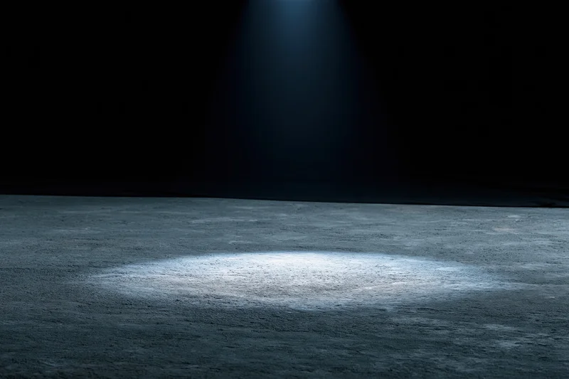 Spotlight on concrete floor in dark studio space