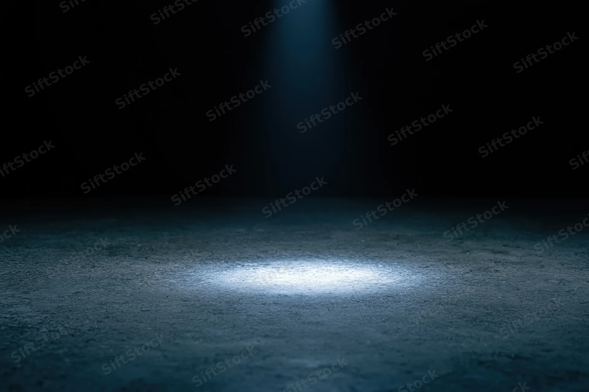 Spotlight on concrete floor in dark studio space