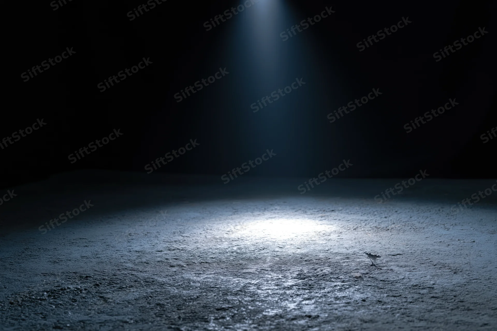 Spotlight beam on empty concrete floor in dark studio space