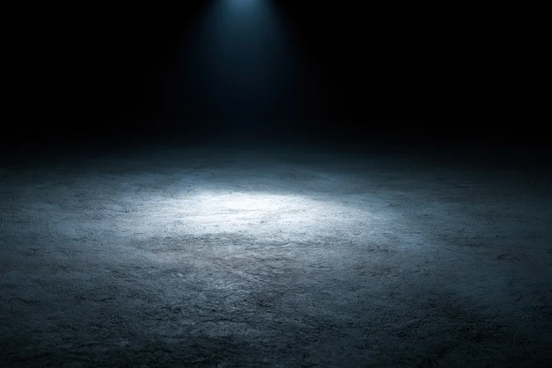 Spotlight on a dark concrete floor in an empty studio space