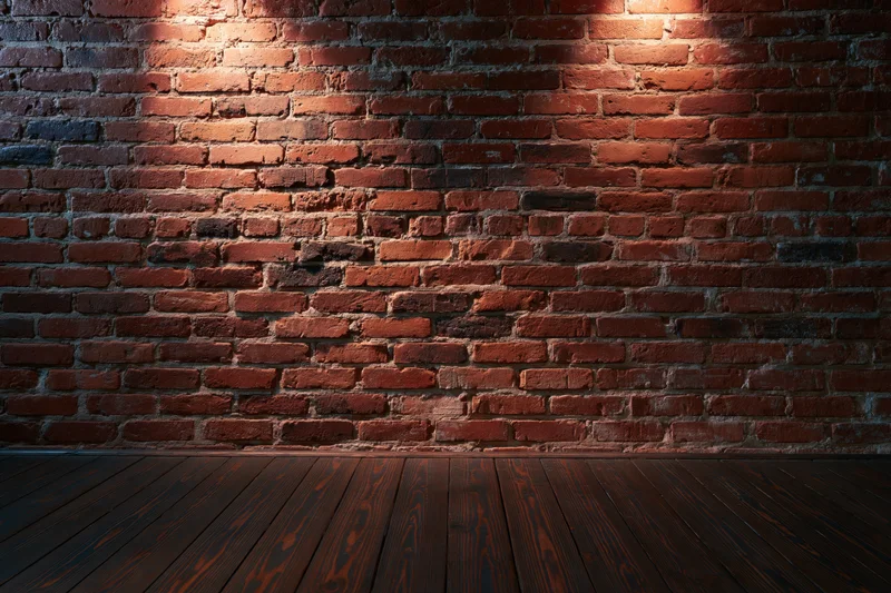 Empty room with aged red brick wall and dark wood floor