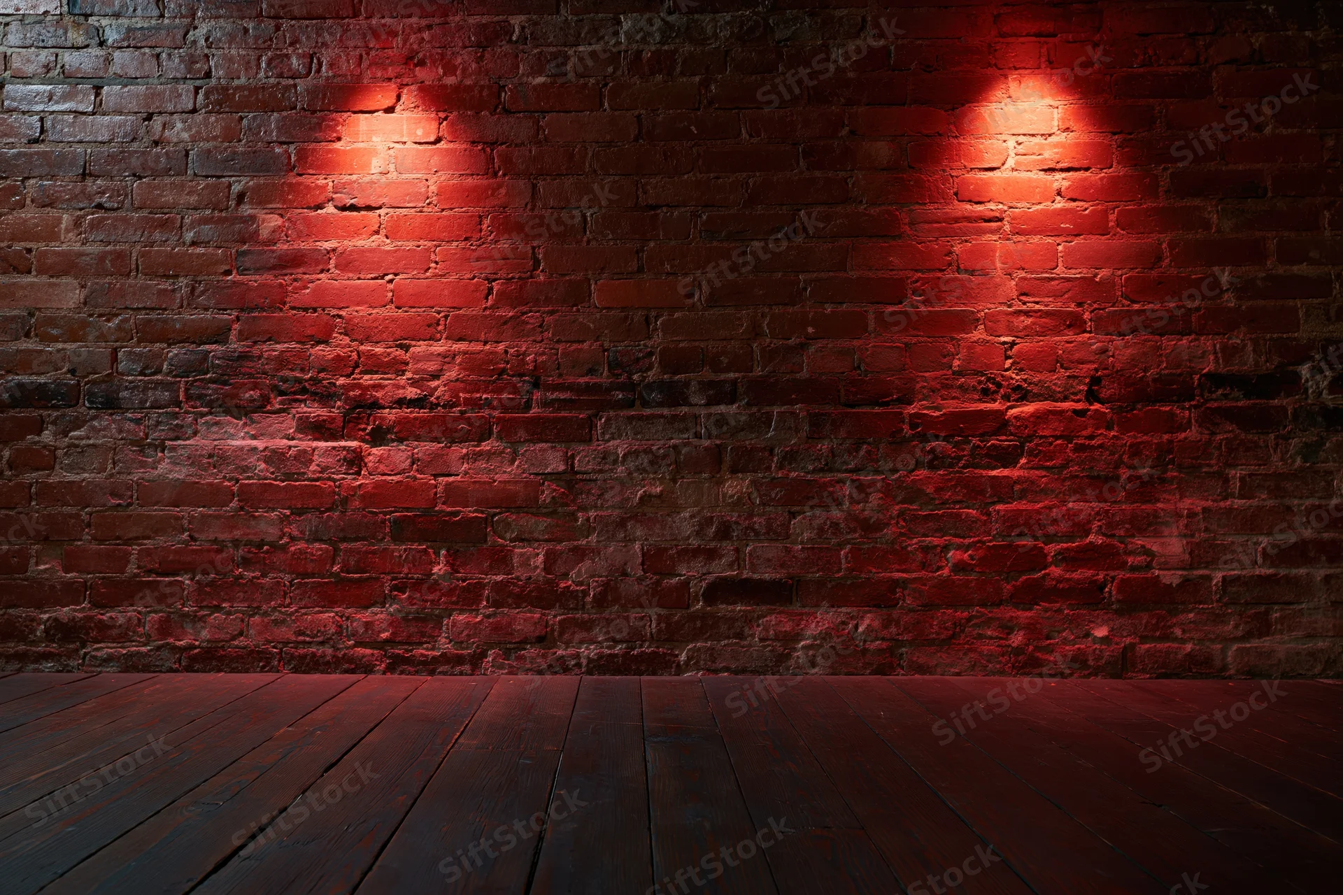 Empty room with aged red brick wall and dark wood floor under red spotlight