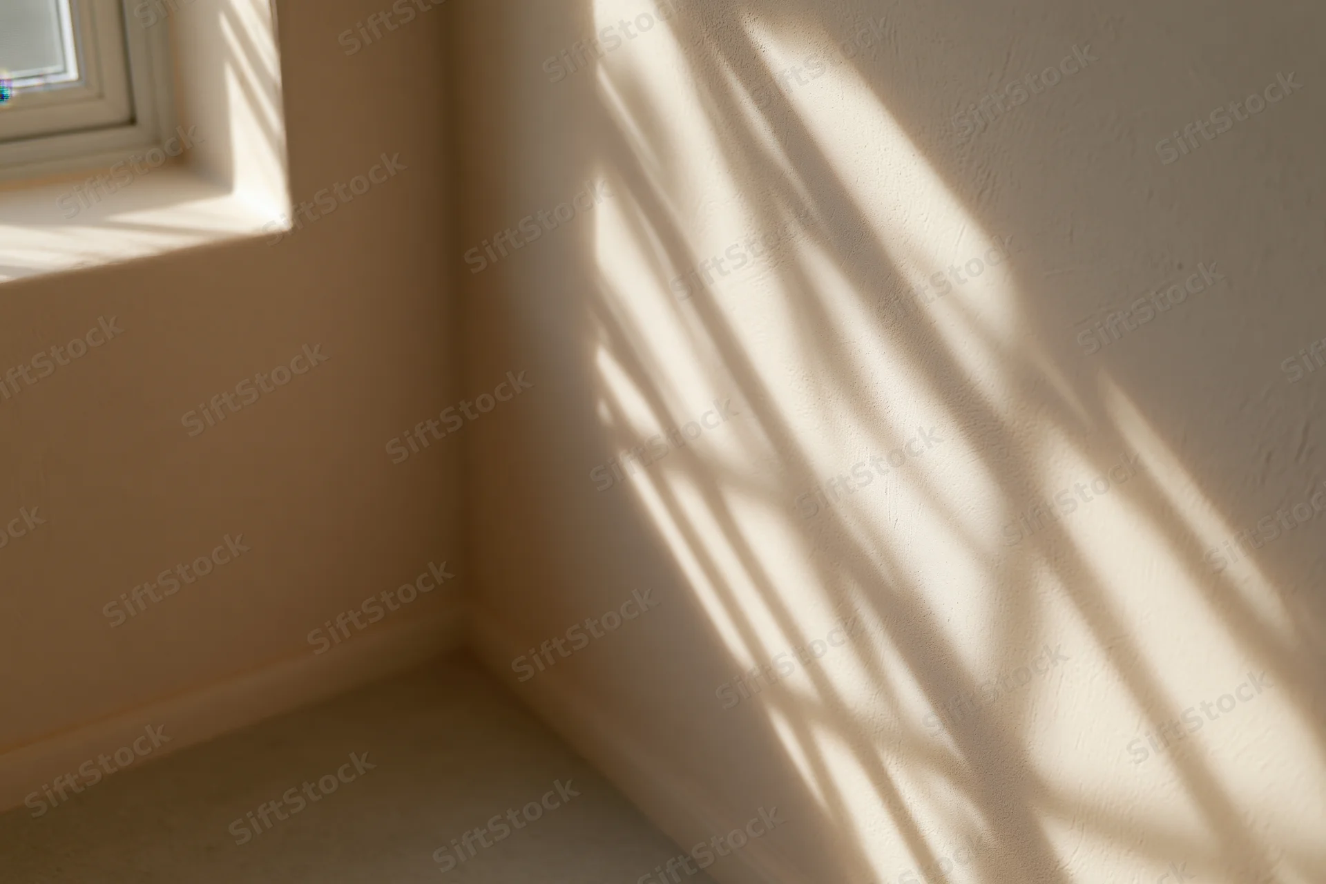 Corner of a minimalist room with sunlight casting shadows on beige walls near a window