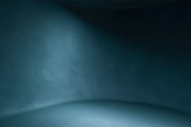 Curved seamless backdrop in a dark blue studio space with soft lighting and copyspace