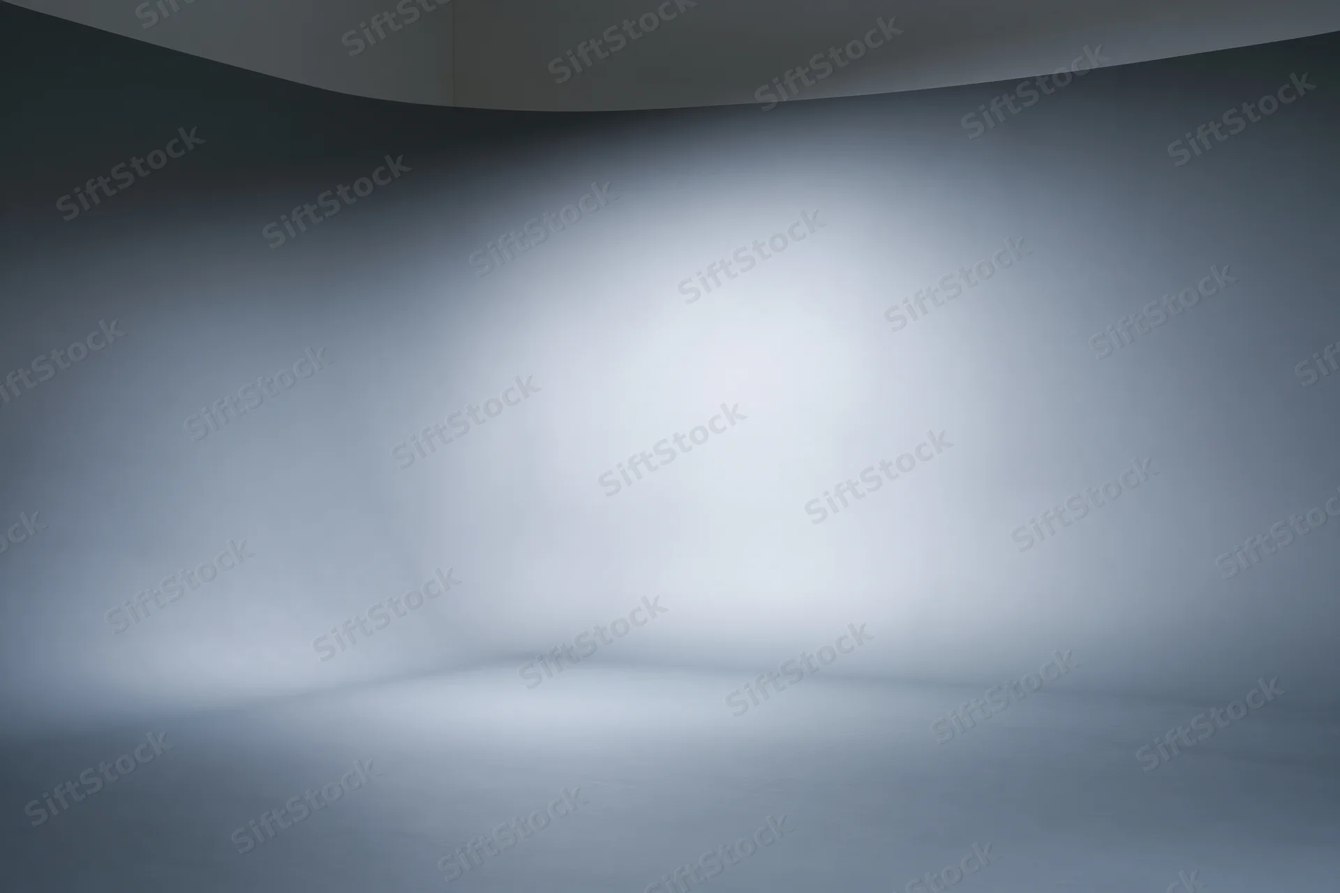 Empty professional photo studio with seamless grey curved backdrop and soft lighting
