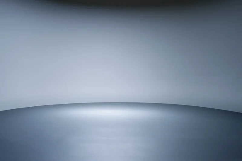Smooth seamless grey backdrop in a professional photo studio with curved surface and soft lighting
