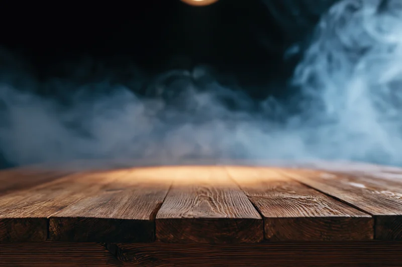 Rustic wooden table surface under spotlight with drifting smoke in dark background